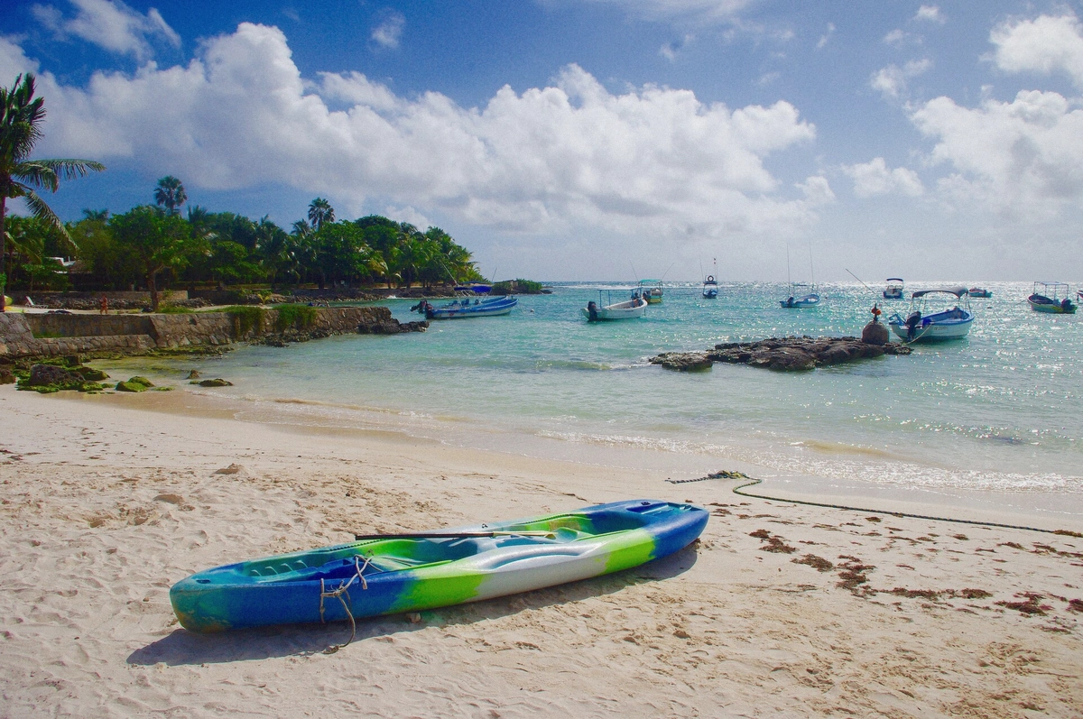 Sandy trail lined with coastal vegetation leading toward the beach at Akumal, Mexico